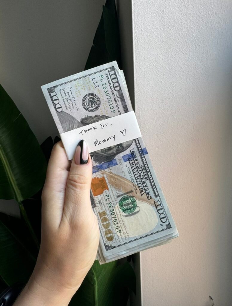 Mistress Blunt holds a stack of cash displaying her findom prowess